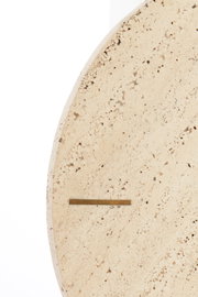 Close-up van een ronde klok van licht, gespikkeld steenmateriaal met een minimalistisch ontwerp, gezien vanaf de zijkant.