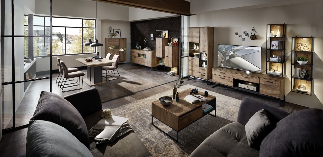 Moderne Wohnzimmermöbel in einem stilvollen Raum mit Esstisch, Stühlen, TV-Unterteil und Regalen aus Holz und Metall, seitliche Perspektive.