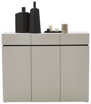 Moderne breite Kommode in hellem Grau mit drei Türen, dekoriert mit schwarzen Vasen und Kerzen, Frontalansicht