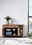 Holz-Sideboard mit zwei Schubladen und offenen Türen, dekoriert mit Pflanzen und Vasen, seitliche Perspektive