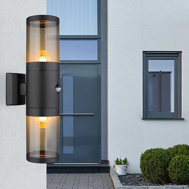 Moderne Außenwandleuchte mit Glaszylinder an Hauswand neben Eingangstür.