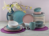 Kombiservice 16-tlg. ModernFas in verschiedenen Pastellfarben, bestehend aus Tellern, Tassen und Schalen, auf einem Tisch mit dekorativen Blumen, seitliche Perspektive.
