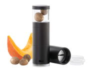 Schwarze Muskatmühle mit transparentem Behälter, gefüllt mit Muskatnüssen, im Vordergrund eine Kürbisscheibe und Muskatnüsse, seitliche Perspektive.