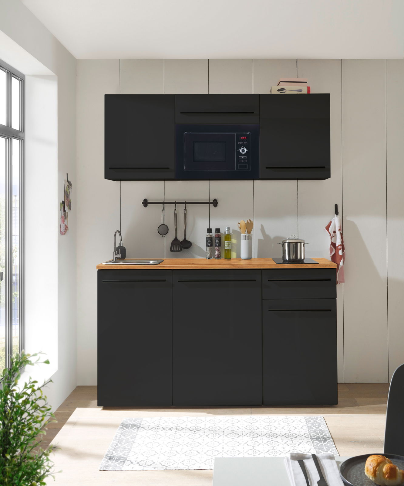 Moderne Single-Küche 160 in schwarzem Design mit Hängeschränken, Mikrowelle, Spüle und Kochfeld, frontal betrachtet.