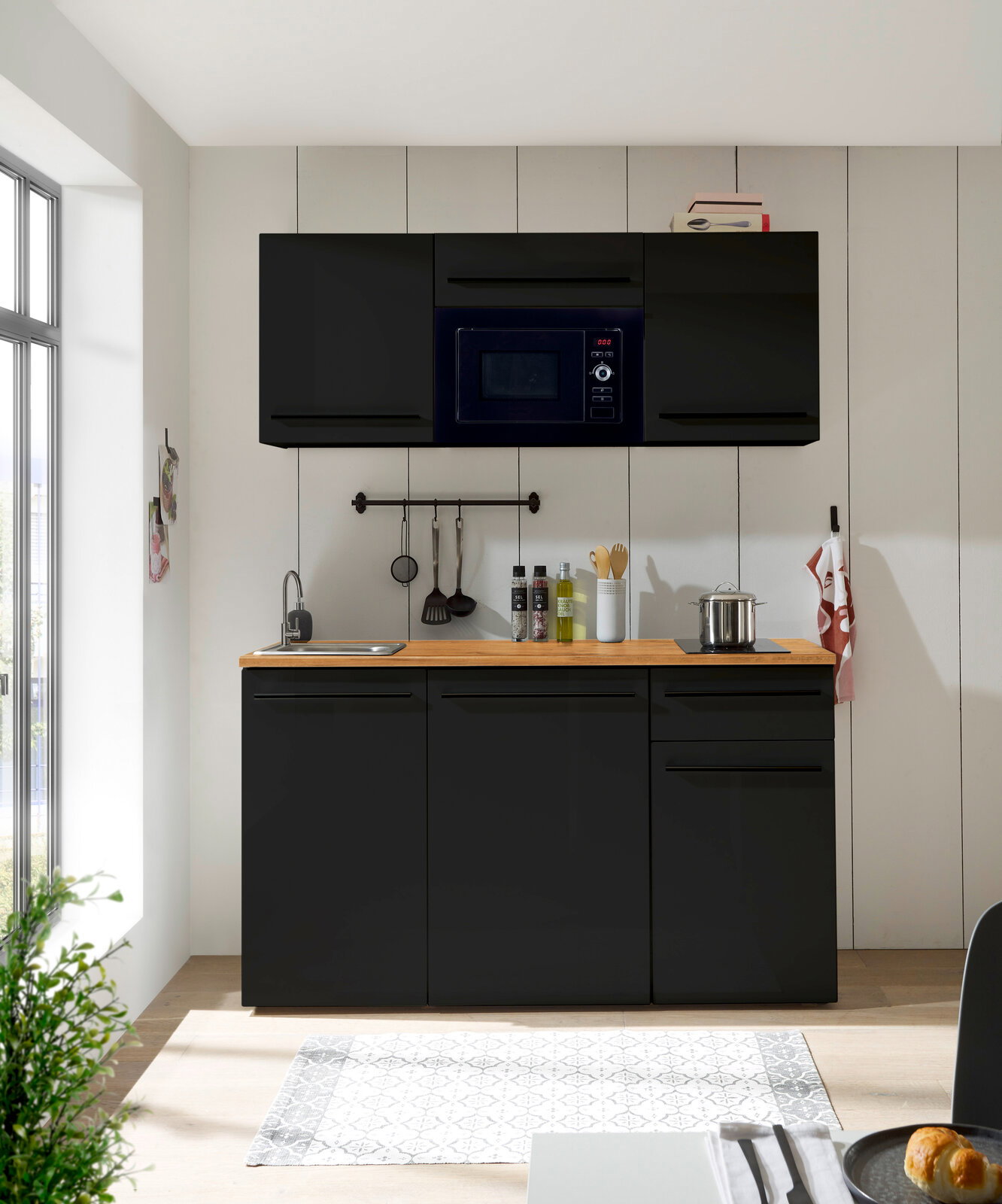 Moderne Single-Küche 160 in schwarzem Design mit Hängeschränken, Mikrowelle, Spüle und Kochfeld, frontal betrachtet.