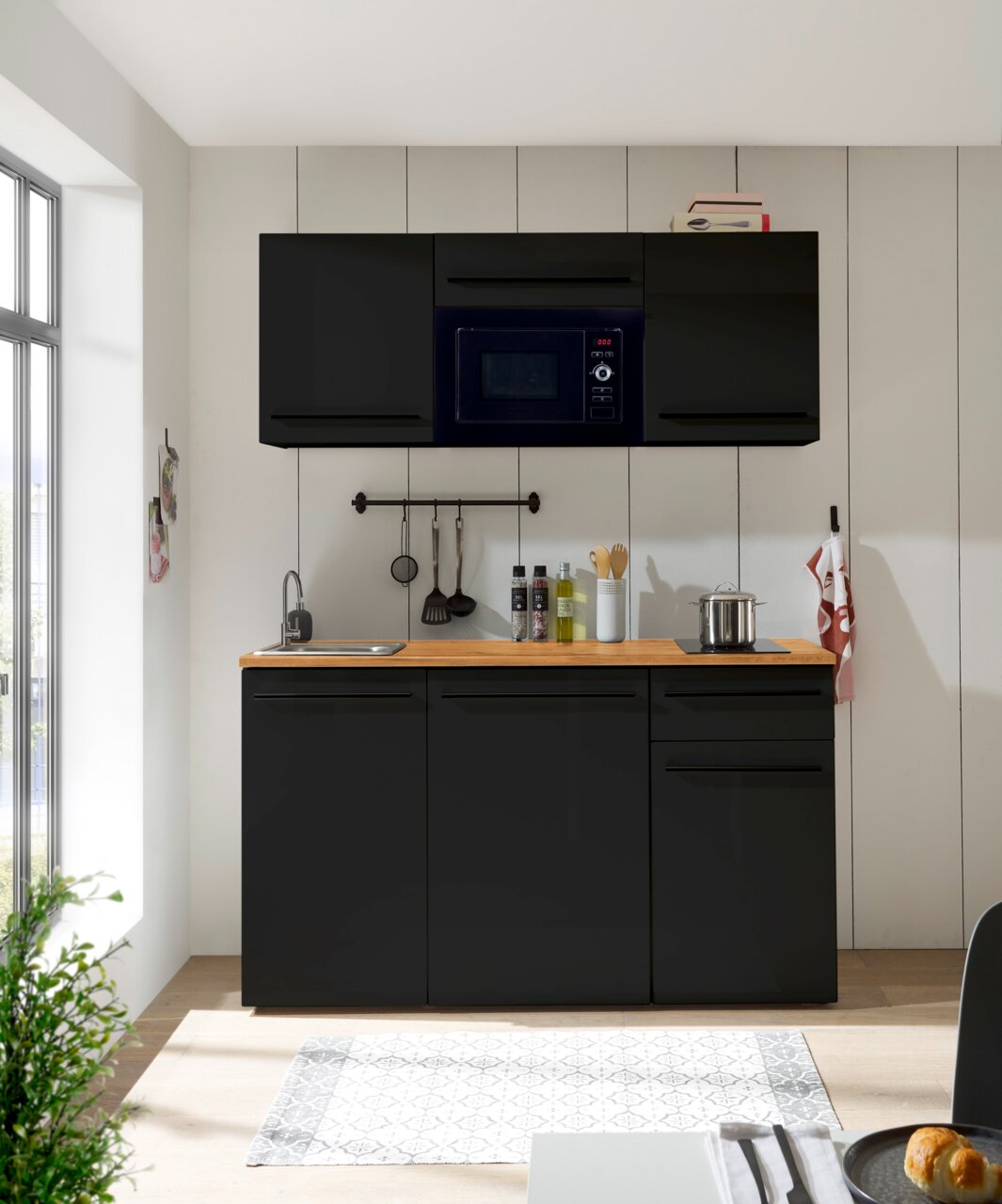 Moderne Single-Küche 160 in schwarzem Design mit Hängeschränken, Mikrowelle, Spüle und Kochfeld, frontal betrachtet.