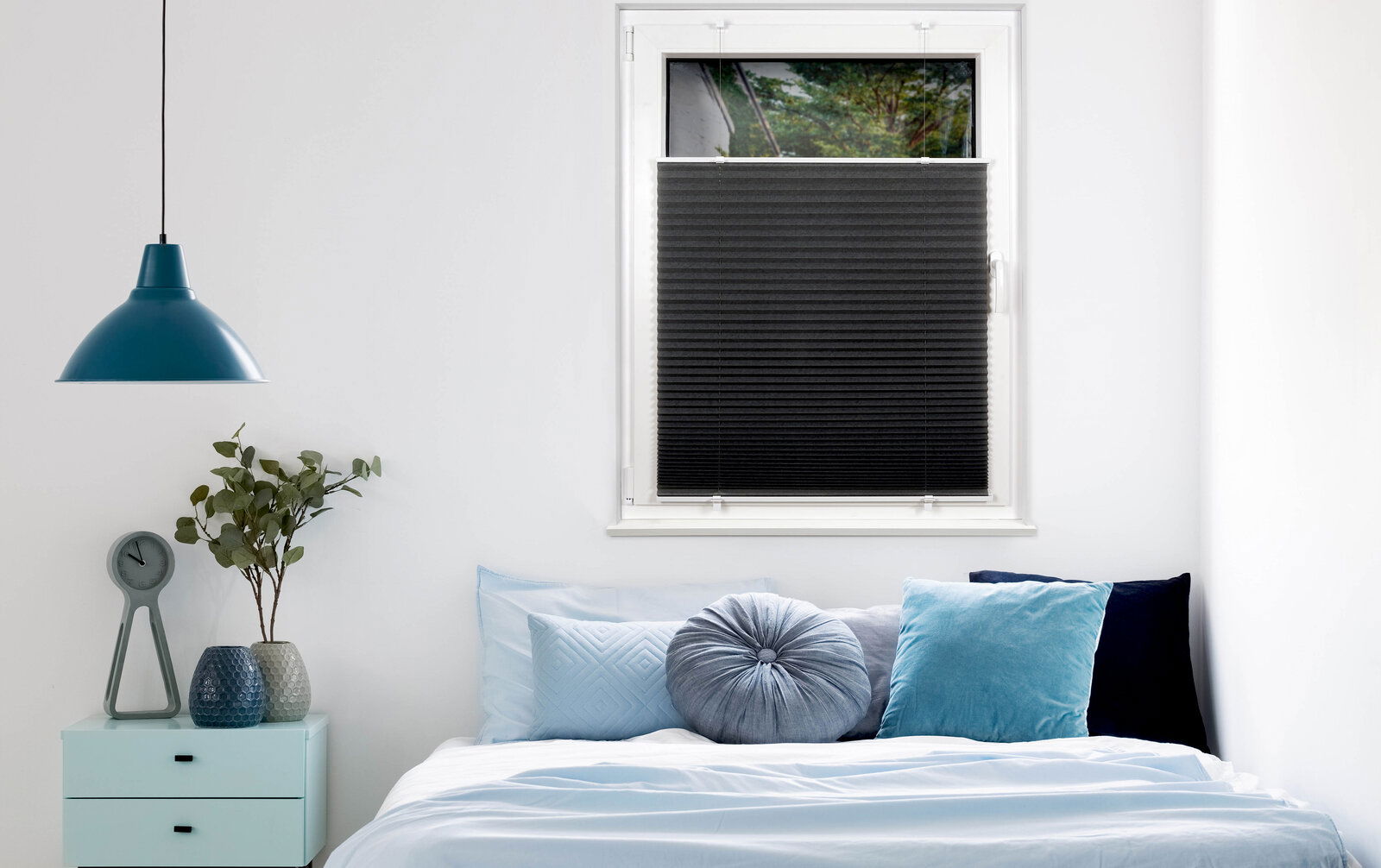 Schwarzes Plissee am Fenster in einem modern eingerichteten Schlafzimmer, seitliche Perspektive