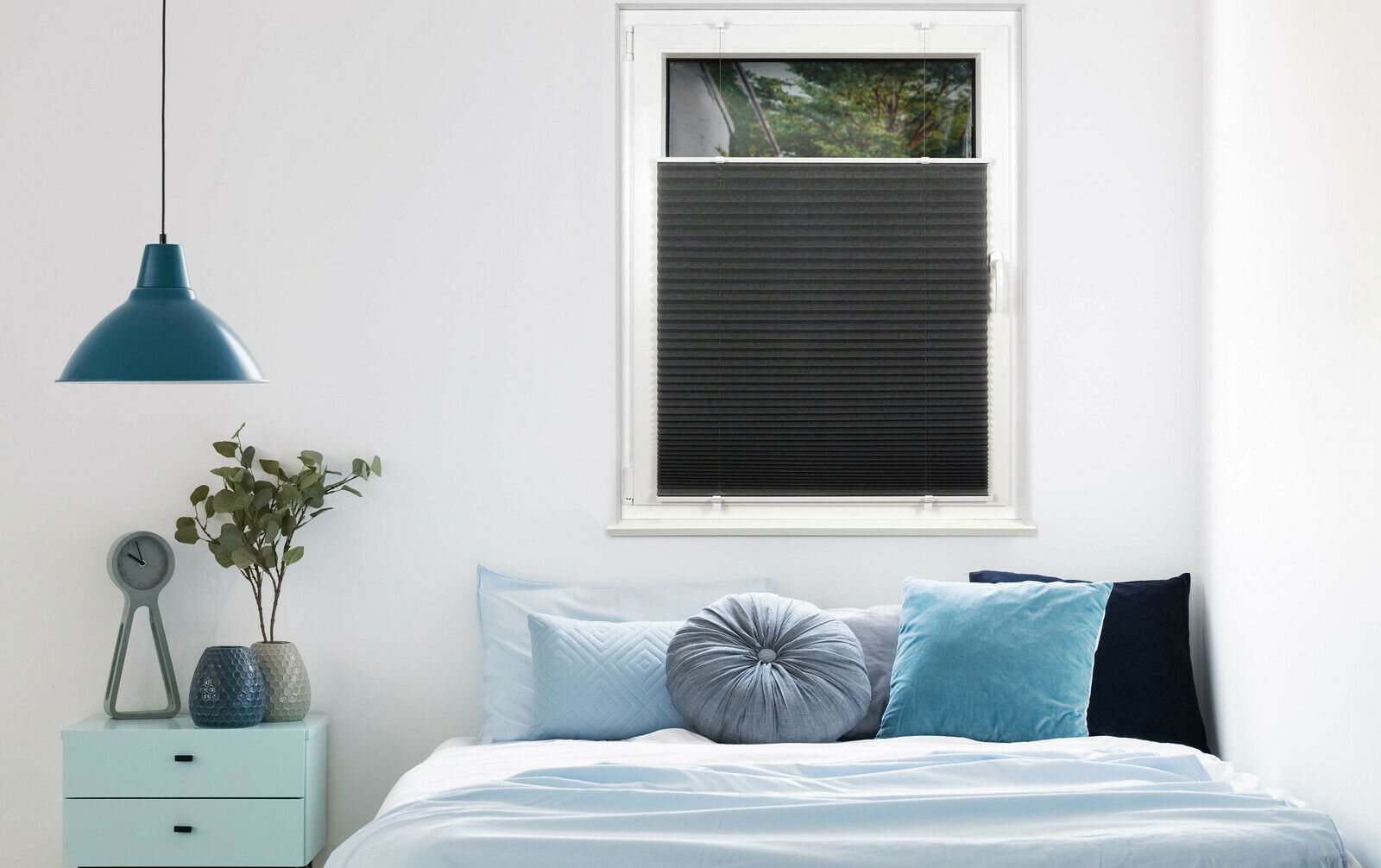 Schwarzes Plissee am Fenster in einem modern eingerichteten Schlafzimmer, seitliche Perspektive