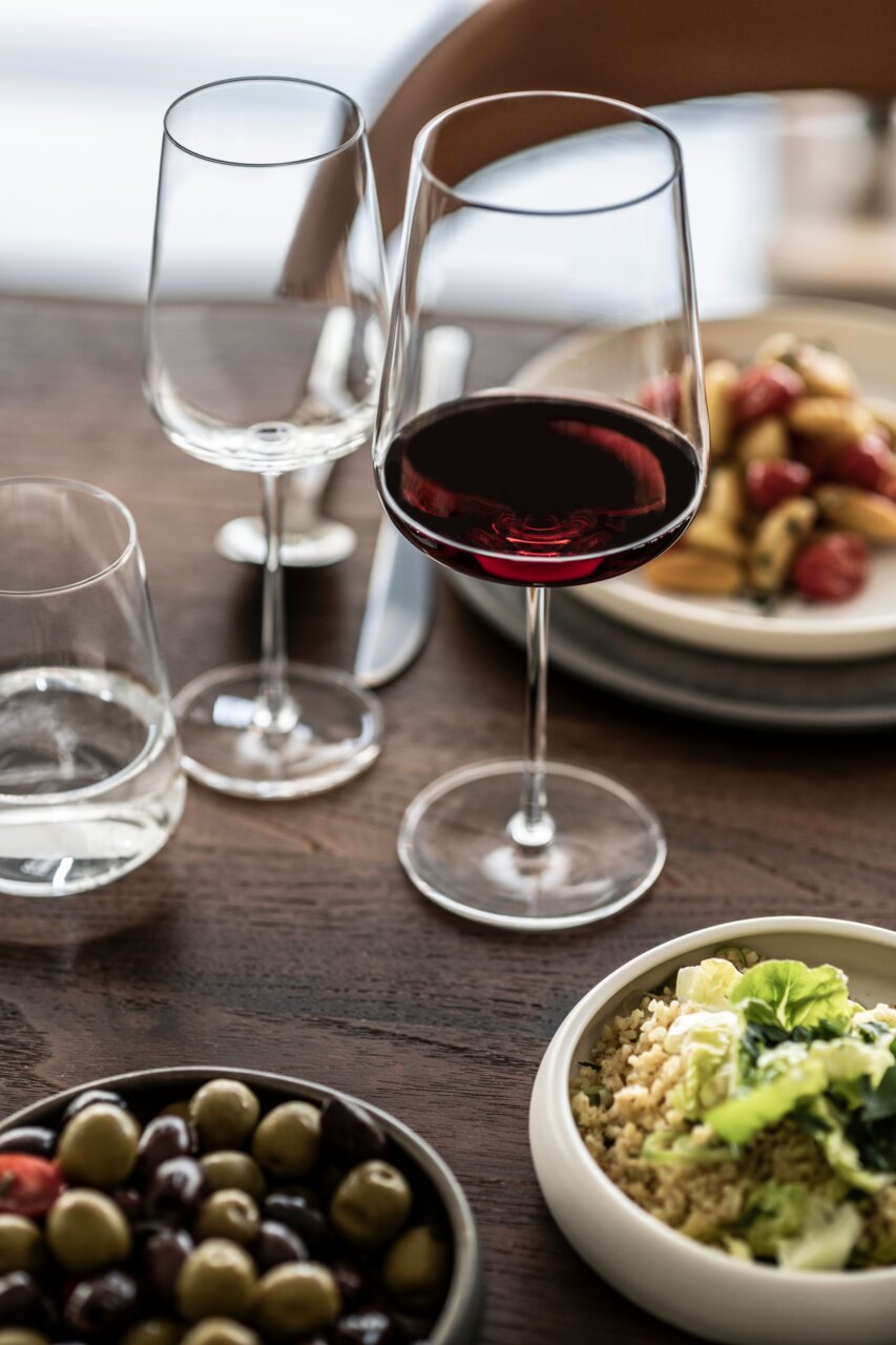 SCHOTT ZWIESEL Rotweinglas VERVINO Bordeaux Rotweinglas auf einem gedeckten Tisch mit Oliven und Salat, seitliche Perspektive
