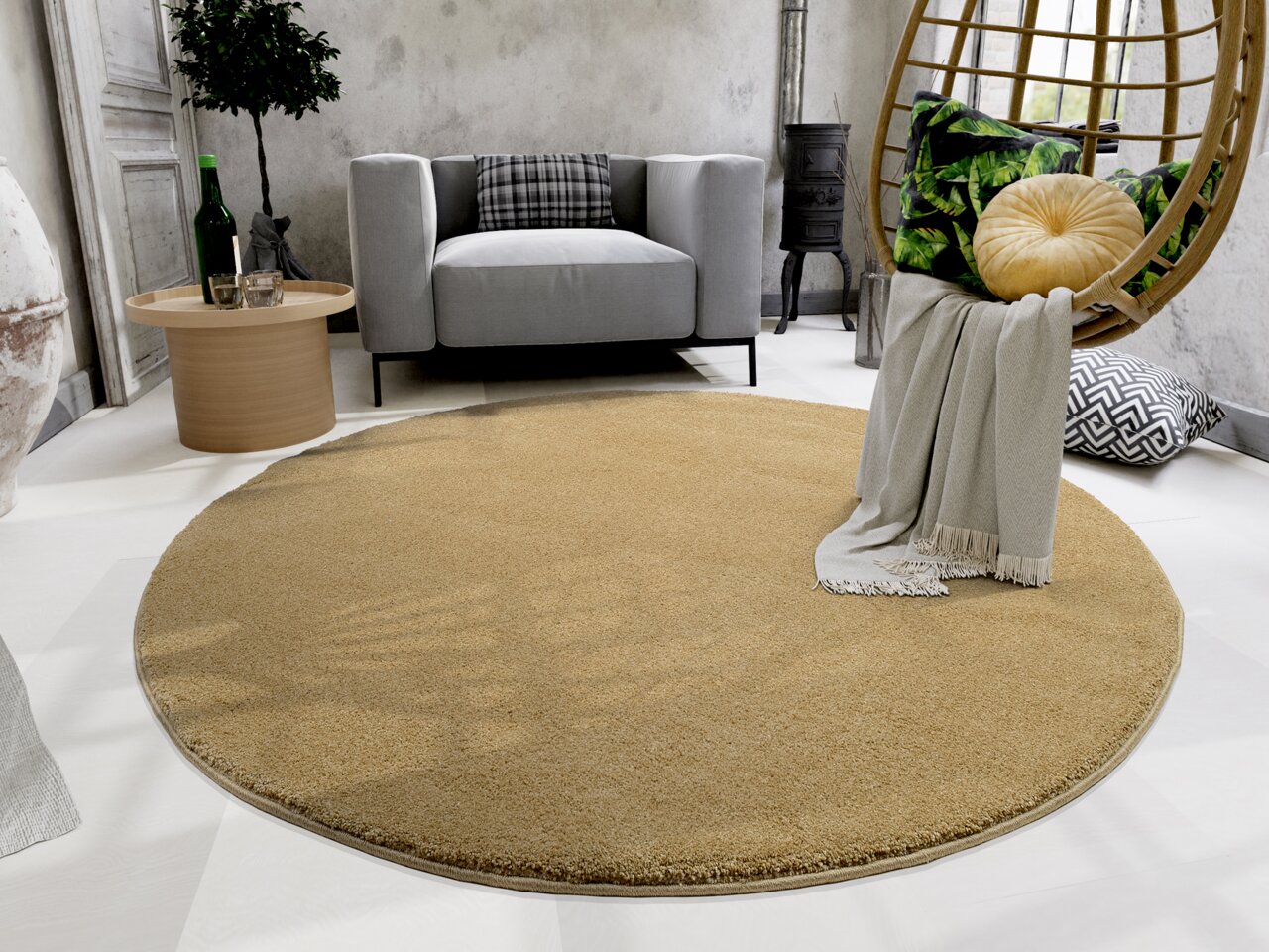 Runder, beiger Uni-Teppich in einem modernen Wohnzimmer mit grauem Sofa, Beistelltisch und Hängesessel. Perspektive von oben.