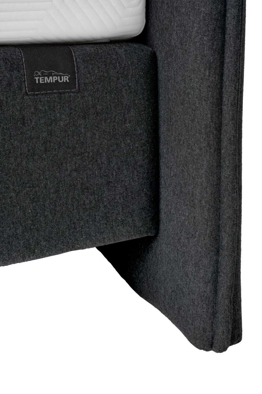 Nahaufnahme eines grauen Boxspringbetts mit TEMPUR-Logo, seitliche Perspektive
