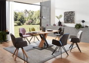 Moderner Essbereich mit einem Esstisch aus Holz und schwarzen Metallbeinen, umgeben von verschiedenen Armlehnstühlen in einem hellen Raum mit Blick auf den Garten.