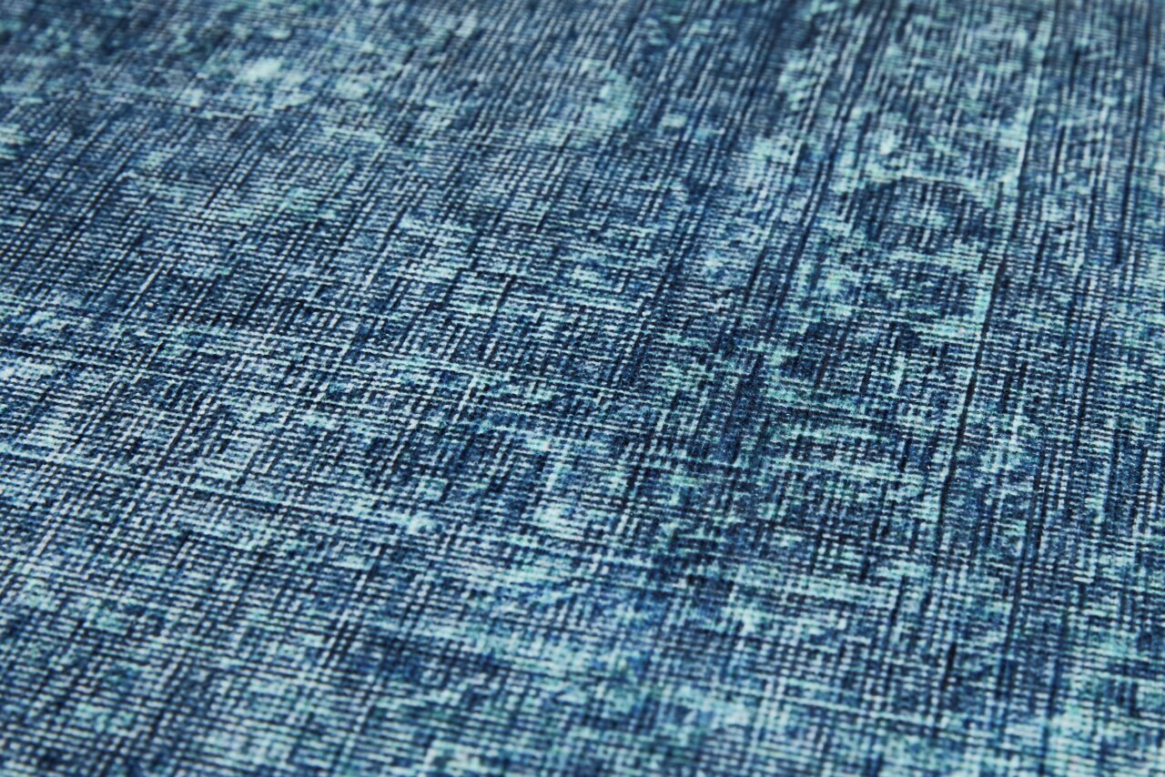 Nahaufnahme eines blauen Teppichs mit abstraktem Muster, schräg von der Seite fotografiert.