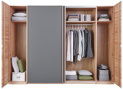 Offener Schwebetürenschrank aus Holz mit grauer Tür, gefüllt mit Kleidung, Kissen und Aufbewahrungsboxen, frontale Ansicht.