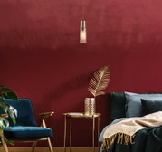 Moderne Hängeleuchte in einem stilvollen Wohnzimmer mit roter Wand, blauer Samtsessel und goldenen Akzenten, seitliche Perspektive.