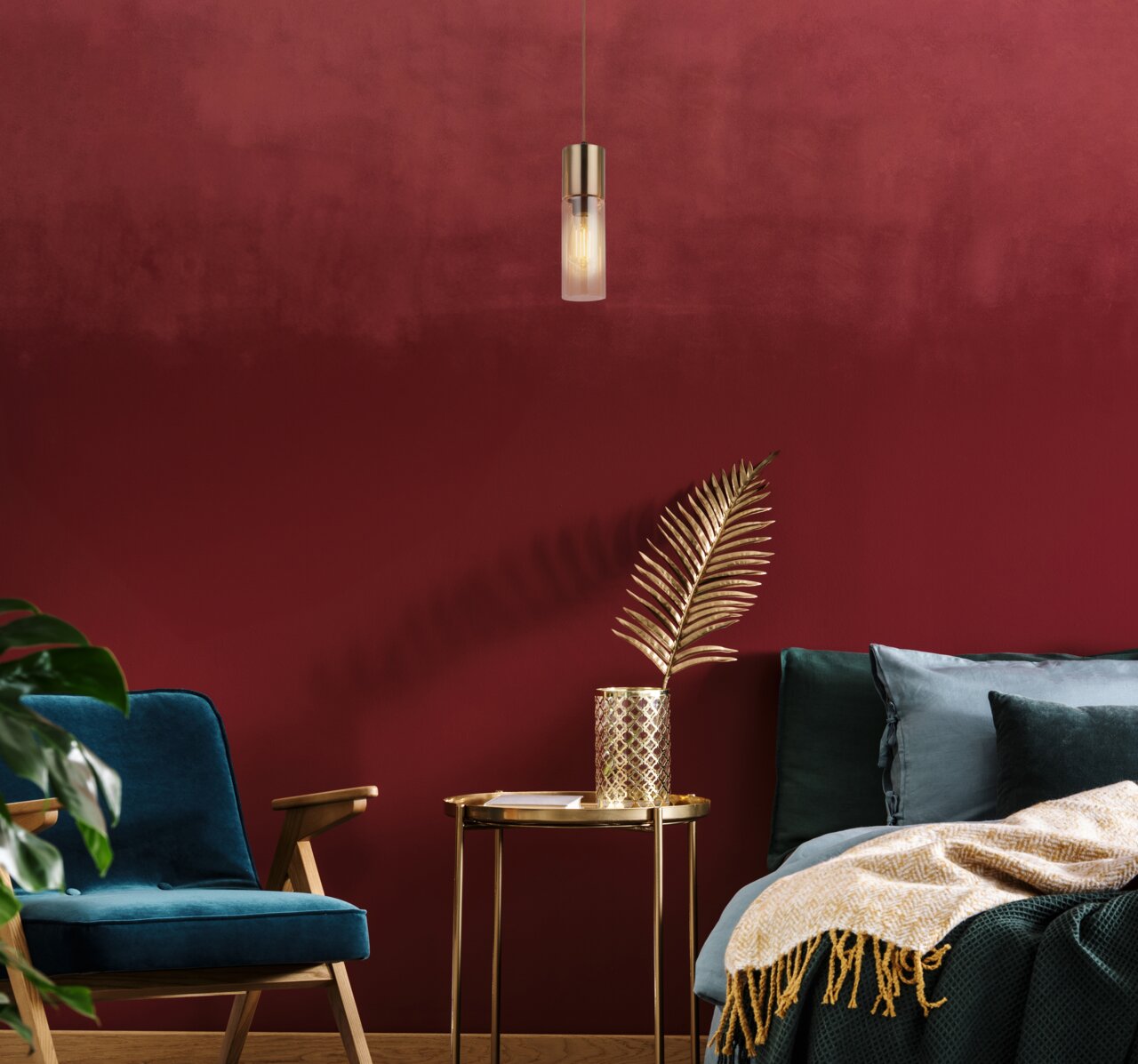 Moderne Hängeleuchte in einem stilvollen Wohnzimmer mit roter Wand, blauer Samtsessel und goldenen Akzenten, seitliche Perspektive.
