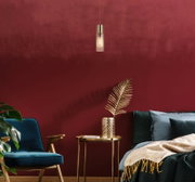 Moderne Hängeleuchte in einem stilvollen Wohnzimmer mit roter Wand, blauer Samtsessel und goldenen Akzenten, seitliche Perspektive.