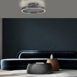 Moderne Deckenleuchte PURE Loop von Paul Neuhaus in einem stilvollen Wohnzimmer, von unten betrachtet.