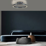 Moderne Deckenleuchte PURE Loop von Paul Neuhaus in einem stilvollen Wohnzimmer, von unten betrachtet.