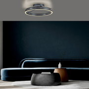 Moderne Deckenleuchte PURE Loop von Paul Neuhaus in einem stilvollen Wohnzimmer, von unten betrachtet.