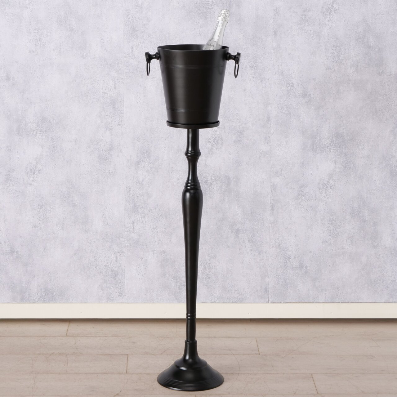 Eleganter, runder Weinkühler Amara auf hohem, schlankem Ständer, frontal abgebildet, mit einer Flasche im Eiskübel.