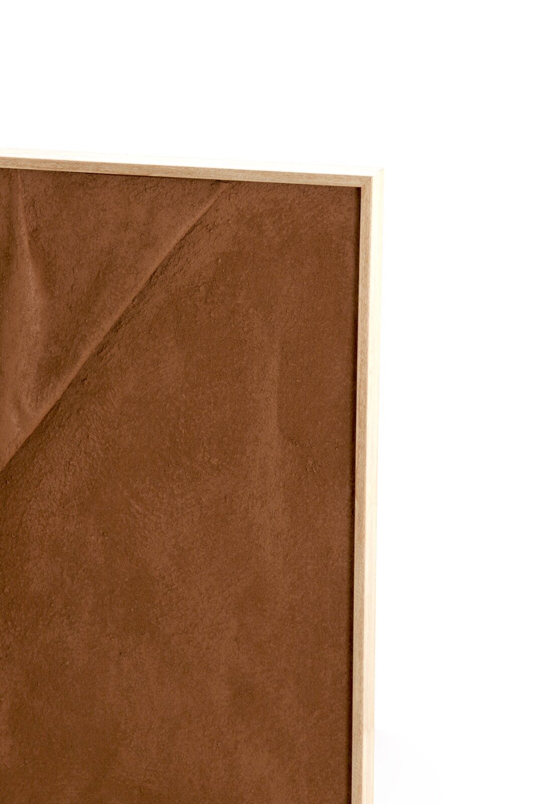 Detailansicht aus leichter Frontperspektive auf eine braune, samtig strukturierte Paneelfläche mit geometrischer Linienprägung und schmalem Rahmen aus hellem Holz