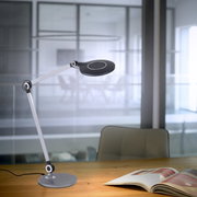 Moderne tafellamp NIKLAS met flexibele arm en ronde lampkop, zijaanzicht op een bureau in een kantoor.