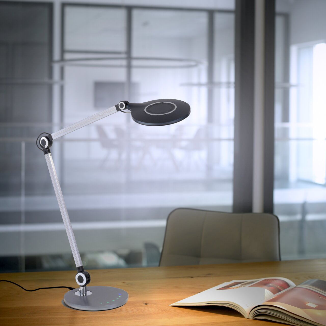 Moderne tafellamp NIKLAS met flexibele arm en ronde lampkop, zijaanzicht op een bureau in een kantoor.