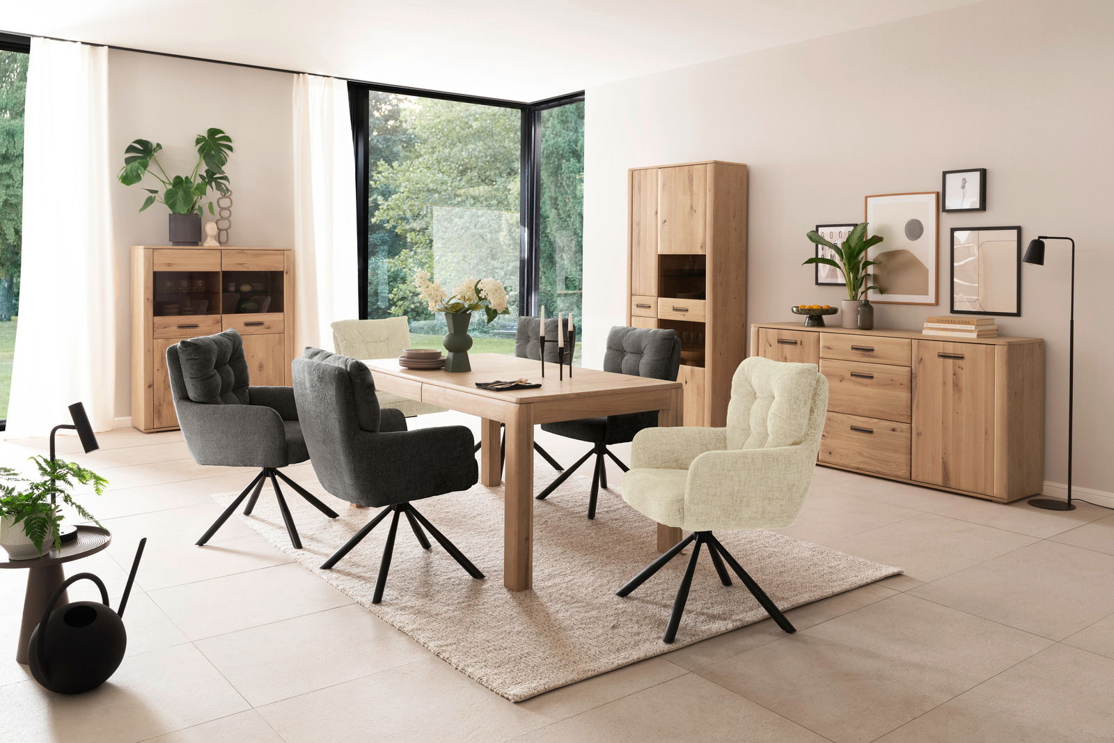 Esszimmer mit modernem Esstisch aus Holz, umgeben von gepolsterten Stühlen in Grau und Beige, mit Blick auf eine helle, von Pflanzen umgebene Fensterfront.