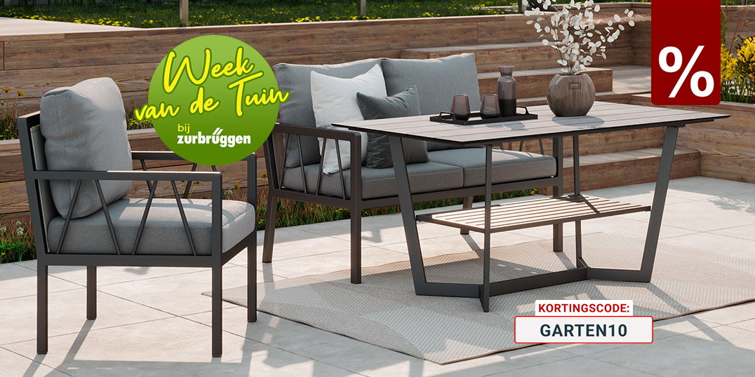 Stijlvolle outdoor lounge met grijze loungemeubels en een moderne tuintafel op een licht terras, omringd door een sfeervol aangelegde tuin.