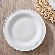 Weißer Teller mit feiner Rillenstruktur, von oben fotografiert, auf einem Holztisch mit geflochtenem Untersetzer.