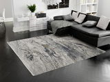 Designer Teppich in einem modernen Wohnzimmer mit dunklem Parkettboden und schwarzem Sofa, aus der Vogelperspektive betrachtet.