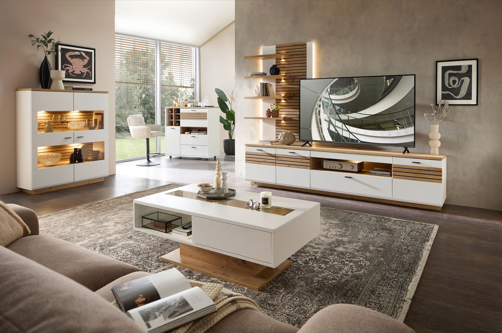 Modernes Wohnzimmer mit stilvollem Raumteiler-Kombi-Element in Weiß und Holzoptik, frontal betrachtet. Integrierte Beleuchtung und dekorative Accessoires schaffen eine gemütliche Atmosphäre.