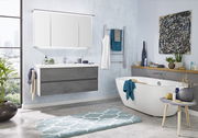 Moderne Badezimmerkombination mit grauem Waschtisch, großem Spiegel und freistehender Badewanne, seitliche Perspektive