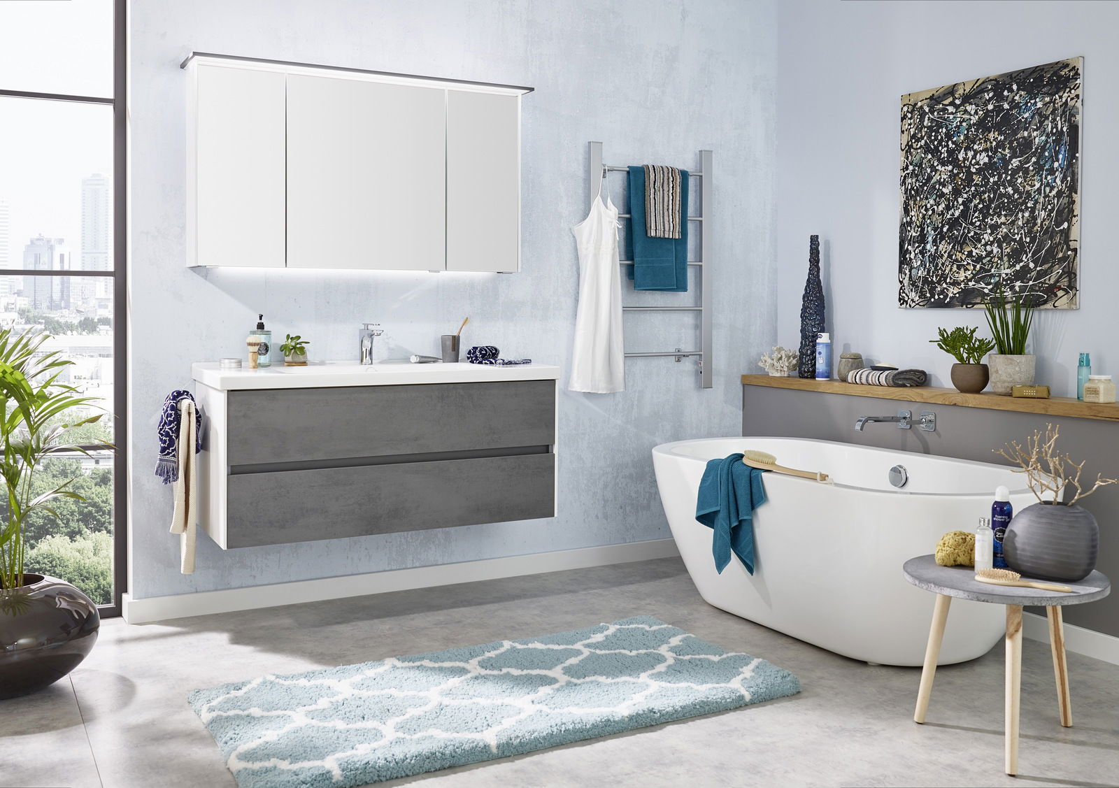 Moderne Badezimmerkombination mit grauem Waschtisch, großem Spiegel und freistehender Badewanne, seitliche Perspektive