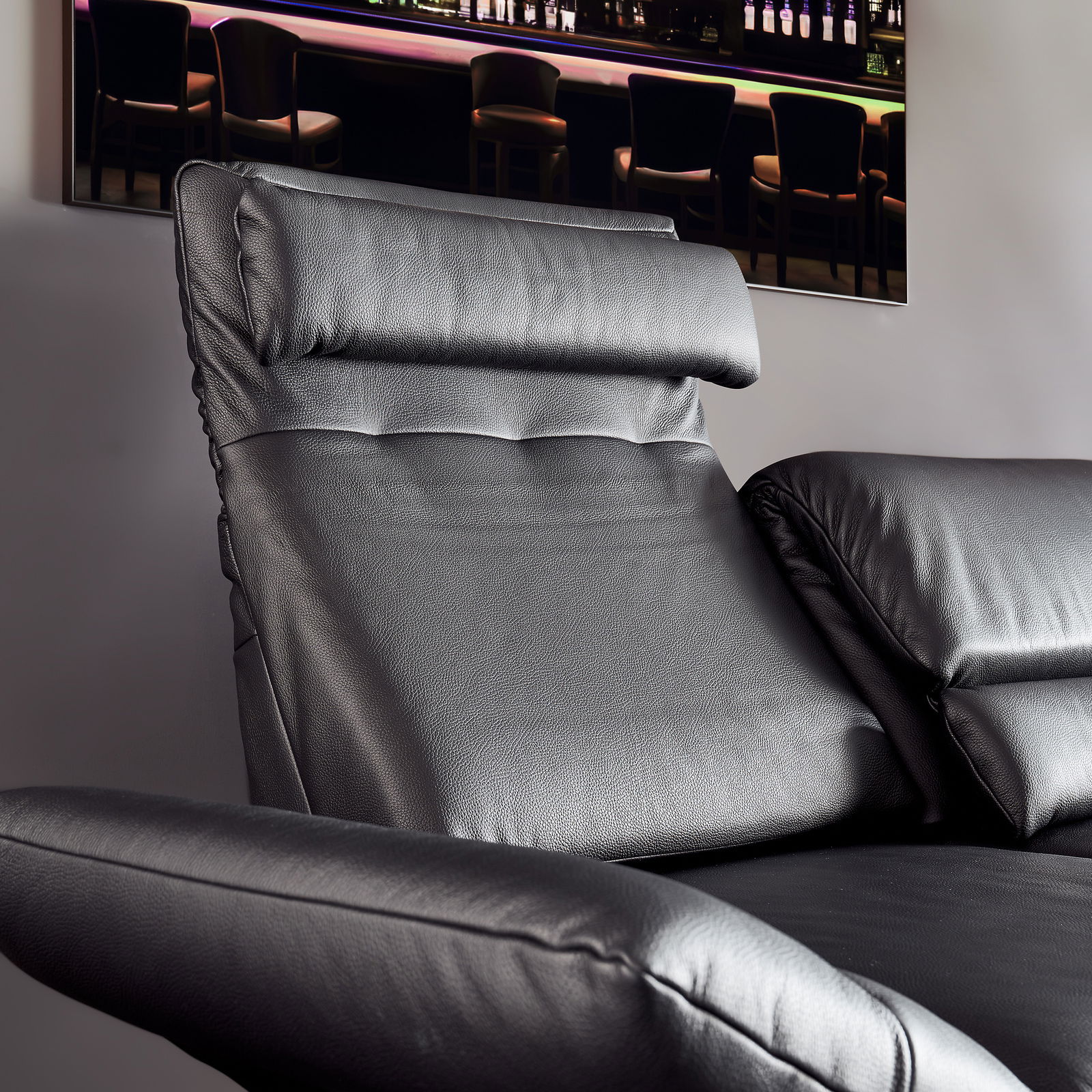 Nahaufnahme eines schwarzen Ledersofas mit verstellbarer Kopfstütze, seitliche Perspektive.
