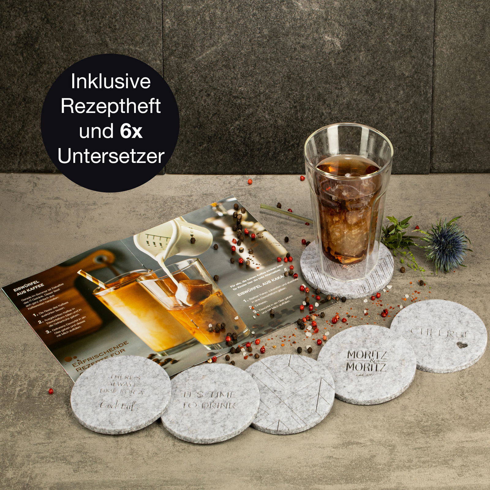 Ein Set aus sechs runden Untersetzern mit verschiedenen Aufschriften, einem Glas mit Getränk und einem Rezeptheft, aus der Vogelperspektive fotografiert.