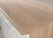 Nahaufnahme einer Küchenarbeitsplatte in Holzoptik mit moderner Metallgriffleiste, Perspektive von oben.