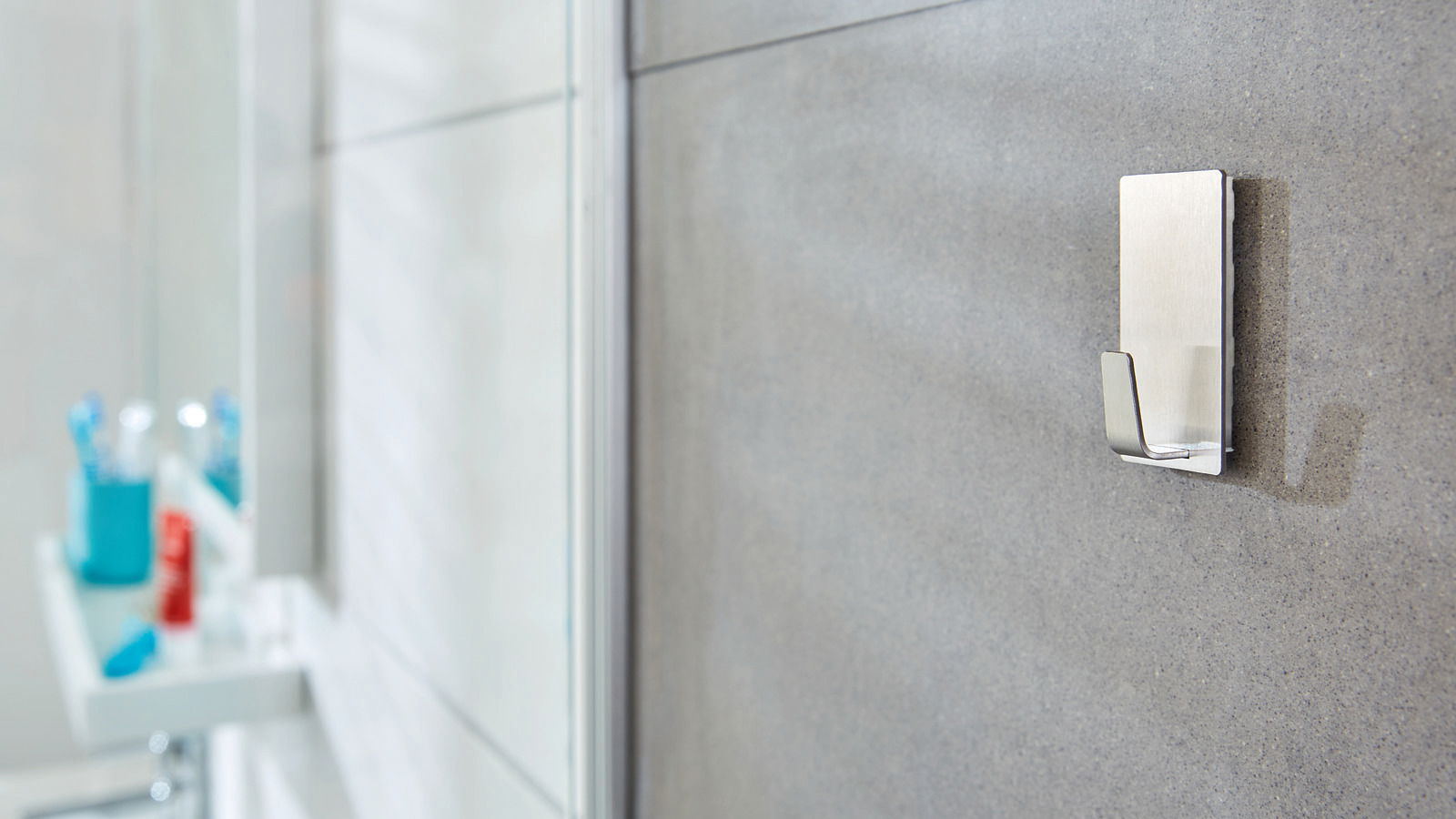 Wandhaken aus Metall, montiert auf einer grauen Badezimmerfliese, seitliche Perspektive