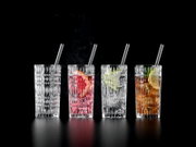Vier hoge, facetgeslepen longdrinkglazen met rietjes op zwarte achtergrond; één leeg en drie met cocktails, ijs en citrus, gefotografeerd in frontaal aanzicht op ooghoogte.