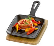 BBQ Grillpfanne mit Holzbrett, von oben fotografiert, mit gegrilltem Fleisch und Paprika garniert.