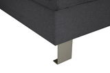 Nahaufnahme einer grauen Sofaecke mit Metallfuß, Perspektive von unten.