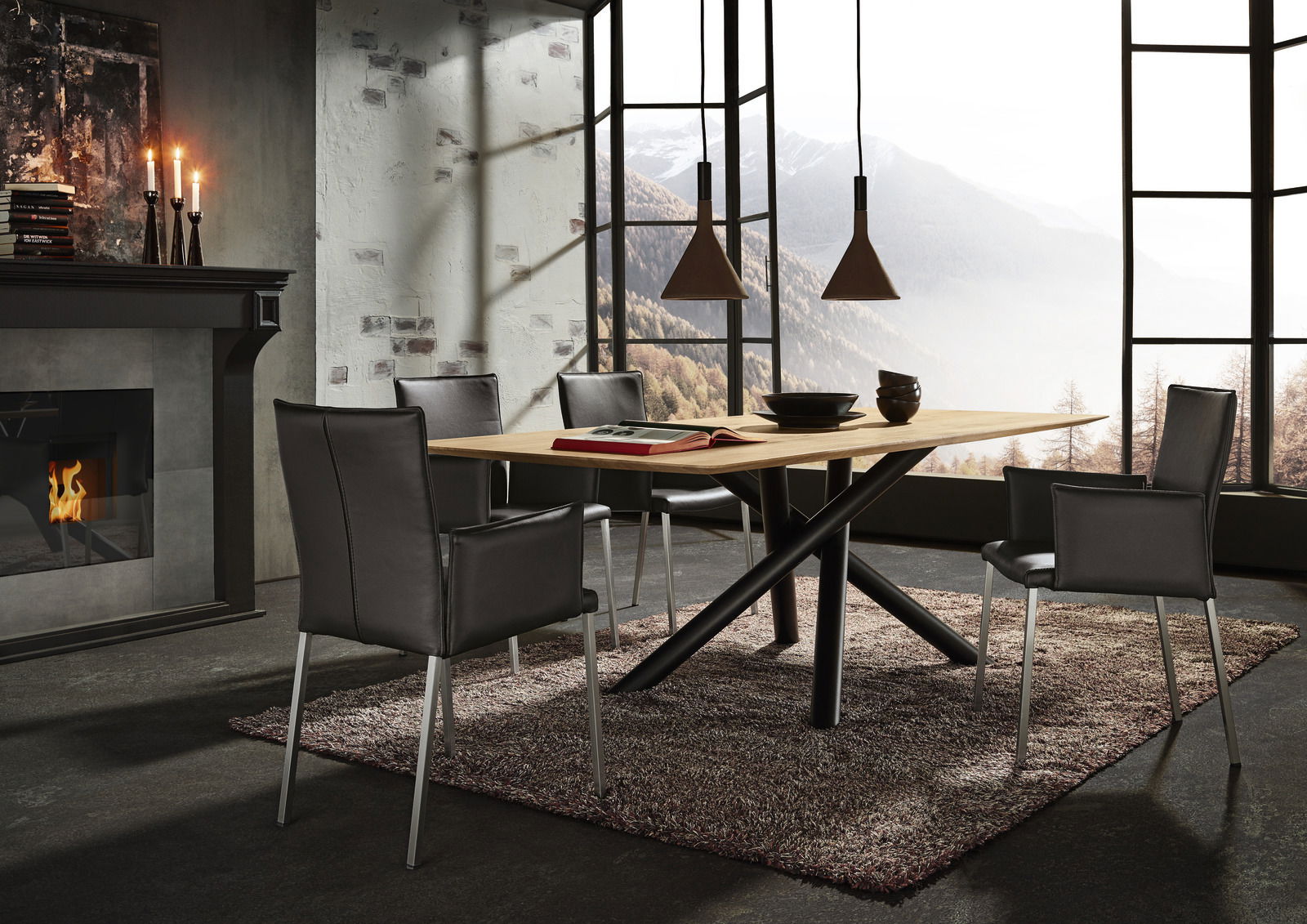 Moderner Esstisch mit Holzplatte und schwarzen Metallbeinen, umgeben von schwarzen Stühlen, in einem stilvollen Raum mit Kamin und Bergblick, seitliche Perspektive.