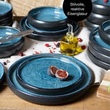 Blaues Tafelservice mit stilvoller, reaktiver Eisenglasur, von oben fotografiert. Enthält Teller und Schalen, dekoriert mit Feigen und Olivenölflasche.