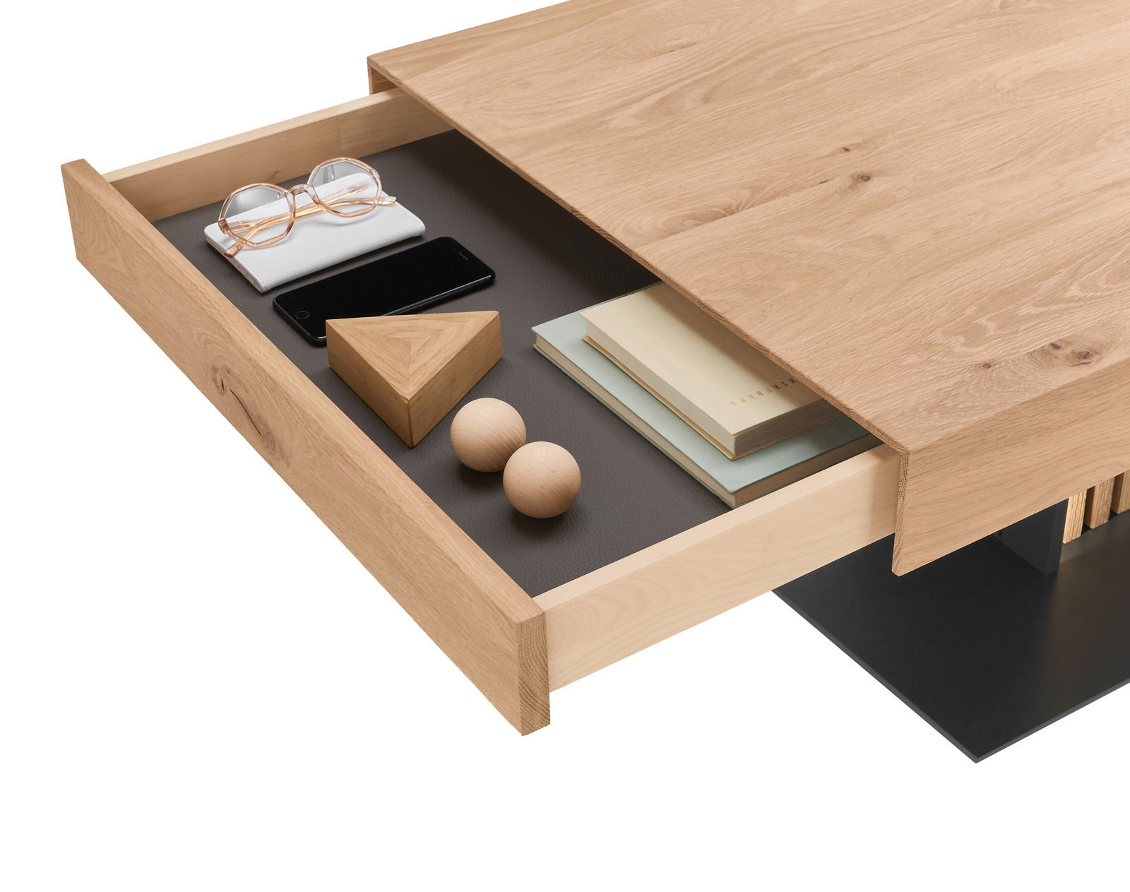 Nahaufnahme eines Couchtisches aus Holz mit geöffneter Schublade, die Bücher, eine Brille, ein Smartphone und dekorative Holzelemente enthält. Perspektive von oben.