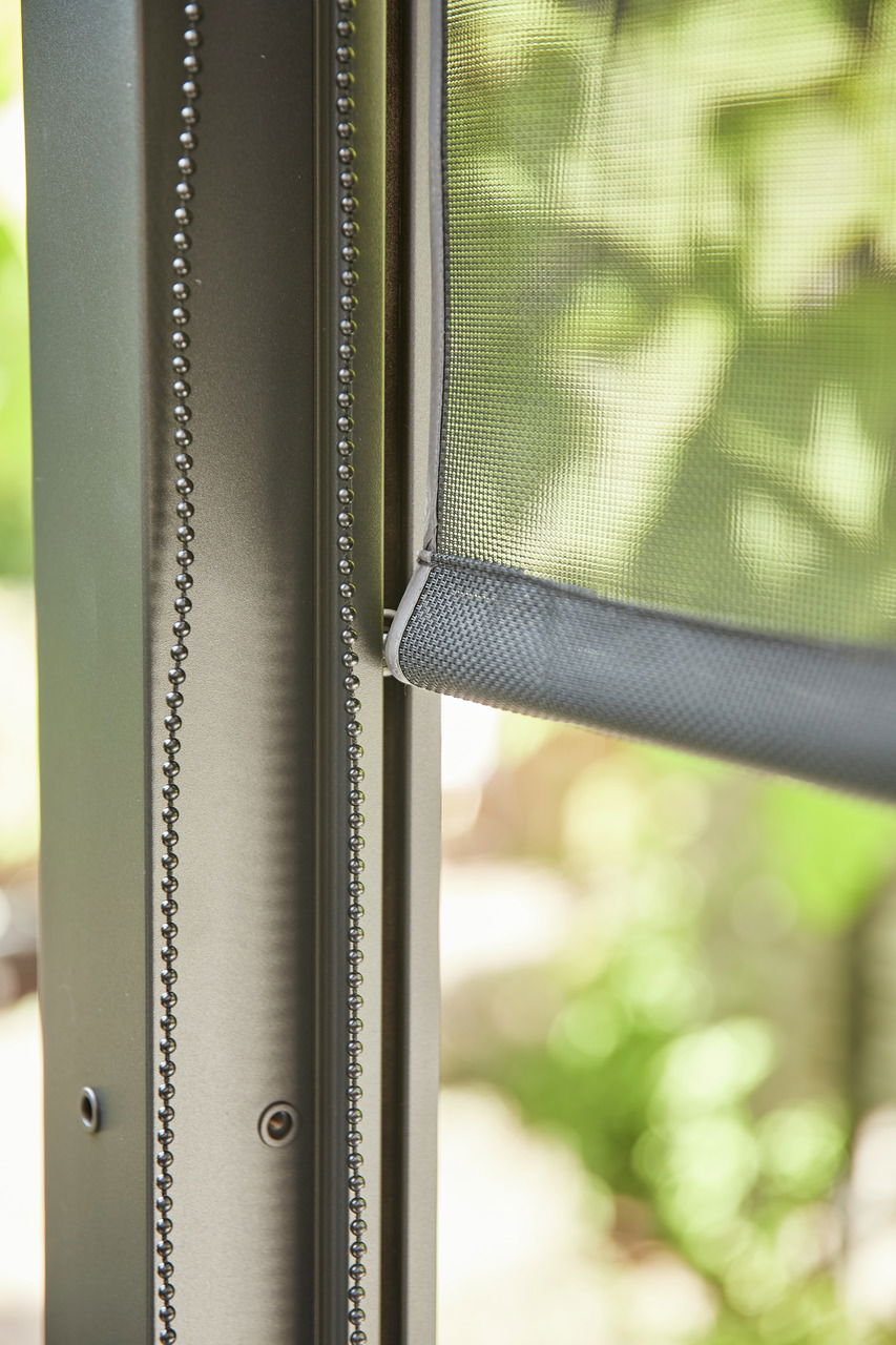 Nahaufnahme eines Rollos mit Kettenzug an einem Fensterrahmen, seitliche Perspektive