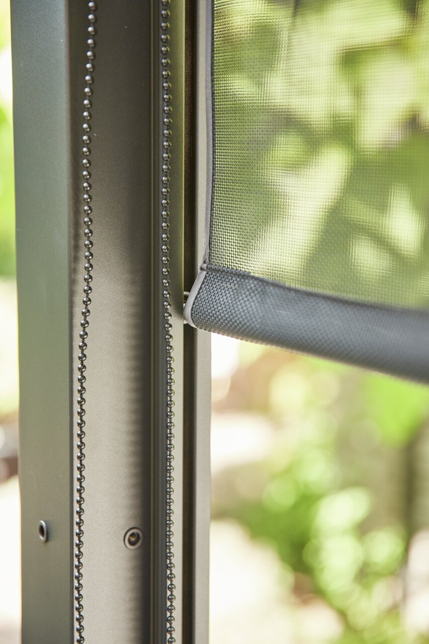 Nahaufnahme eines Rollos mit Kettenzug an einem Fensterrahmen, seitliche Perspektive