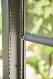 Nahaufnahme eines Rollos mit Kettenzug an einem Fensterrahmen, seitliche Perspektive