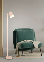 Moderne Akku-Stehleuchte in hellem Beige, neben einem grünen Sessel mit Decke, seitliche Perspektive.