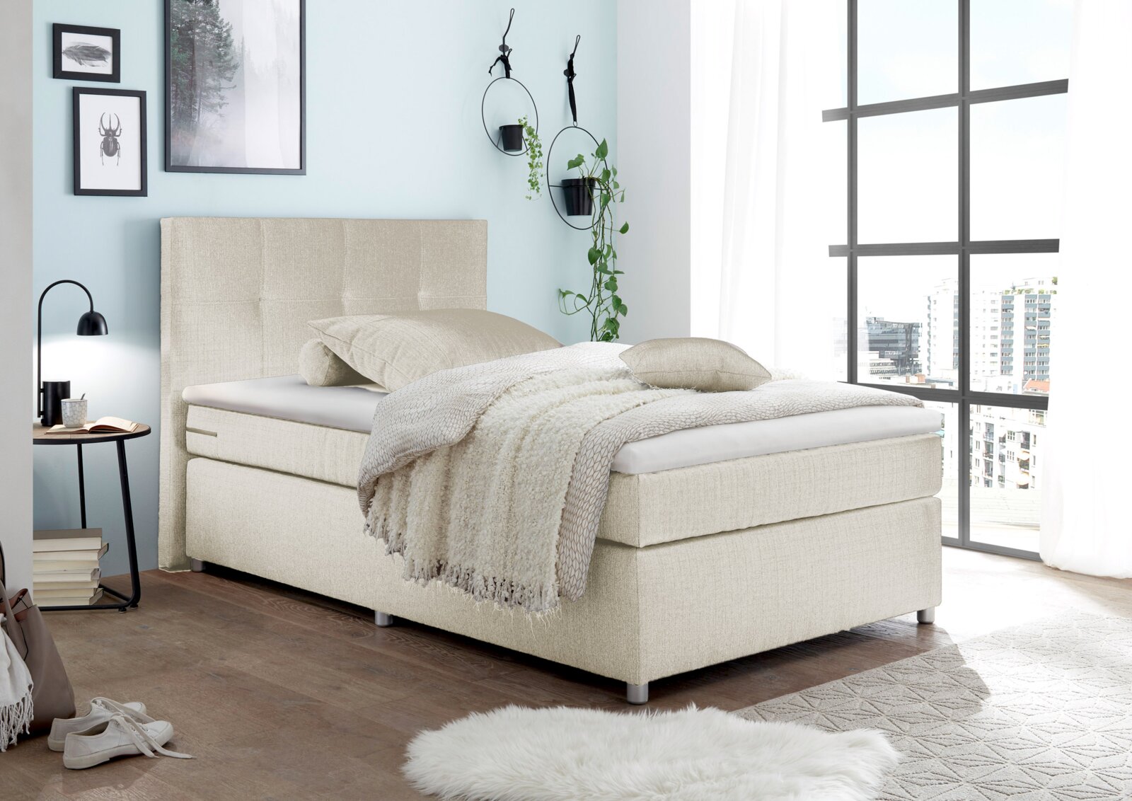Beiges Boxspringbett in modernem Schlafzimmer, seitliche Perspektive